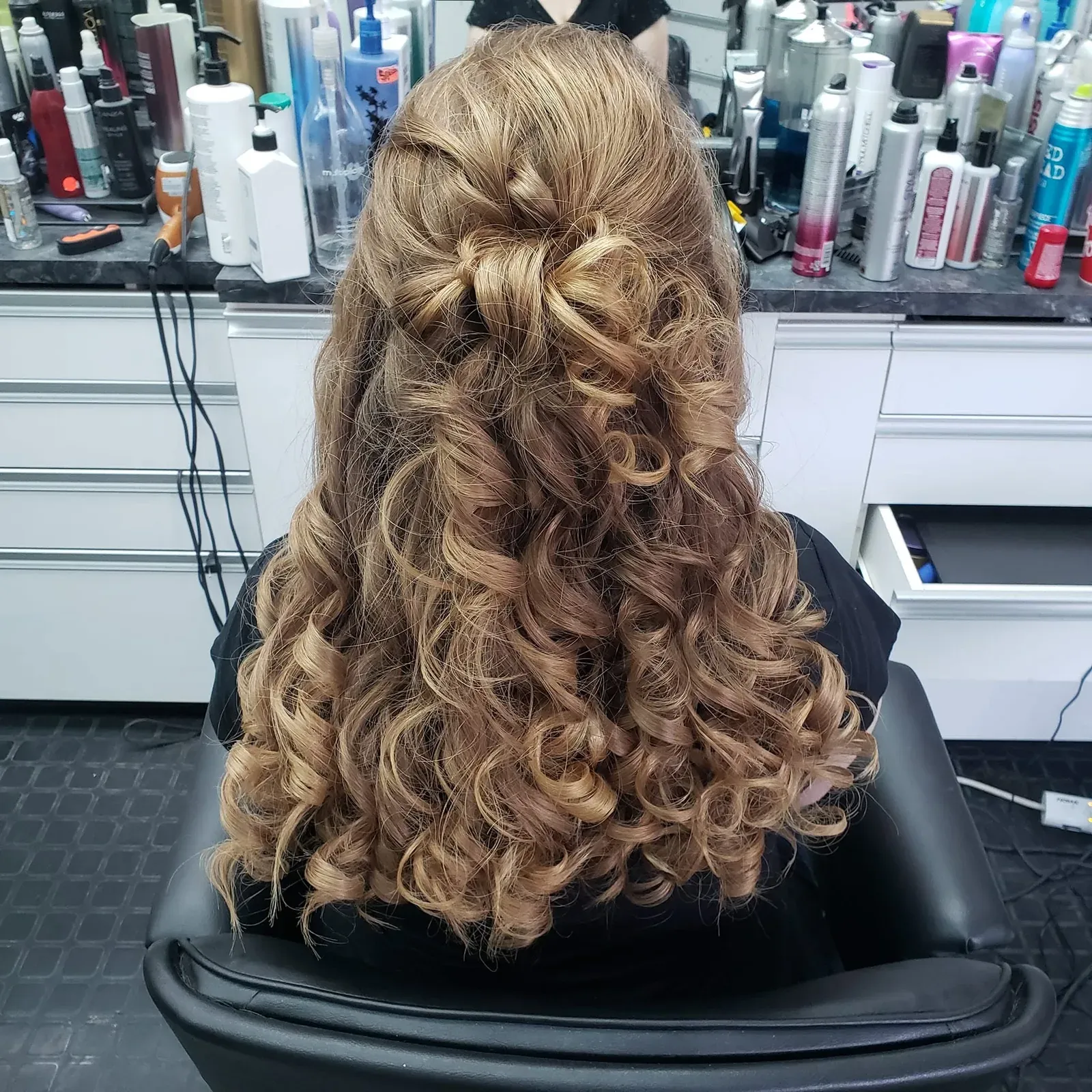 Longues boucles blondes sur un demi-attaché, photographiées de dos dans le salon